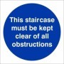 This Staircase Must Be Kept Clear Of All Obstructions mandatory sign with white text on a blue circular background